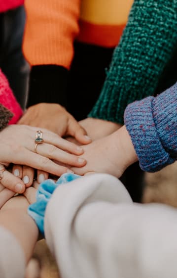 A photo of a group of people's hands together in the middle.