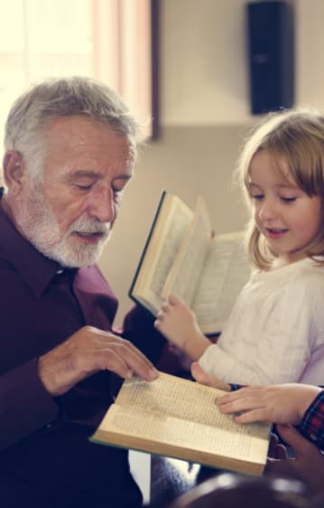 A man with a young girl, reading a bible.