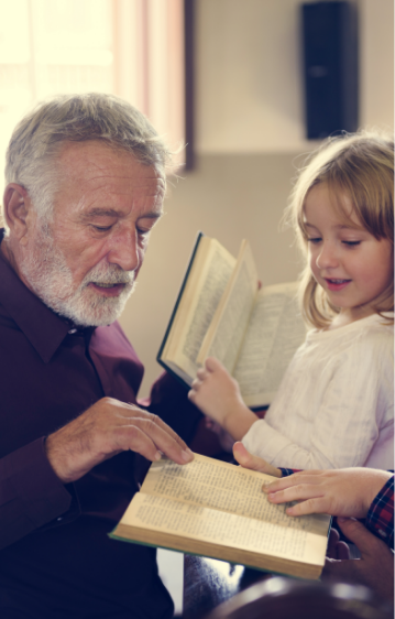 older man reading with young girl