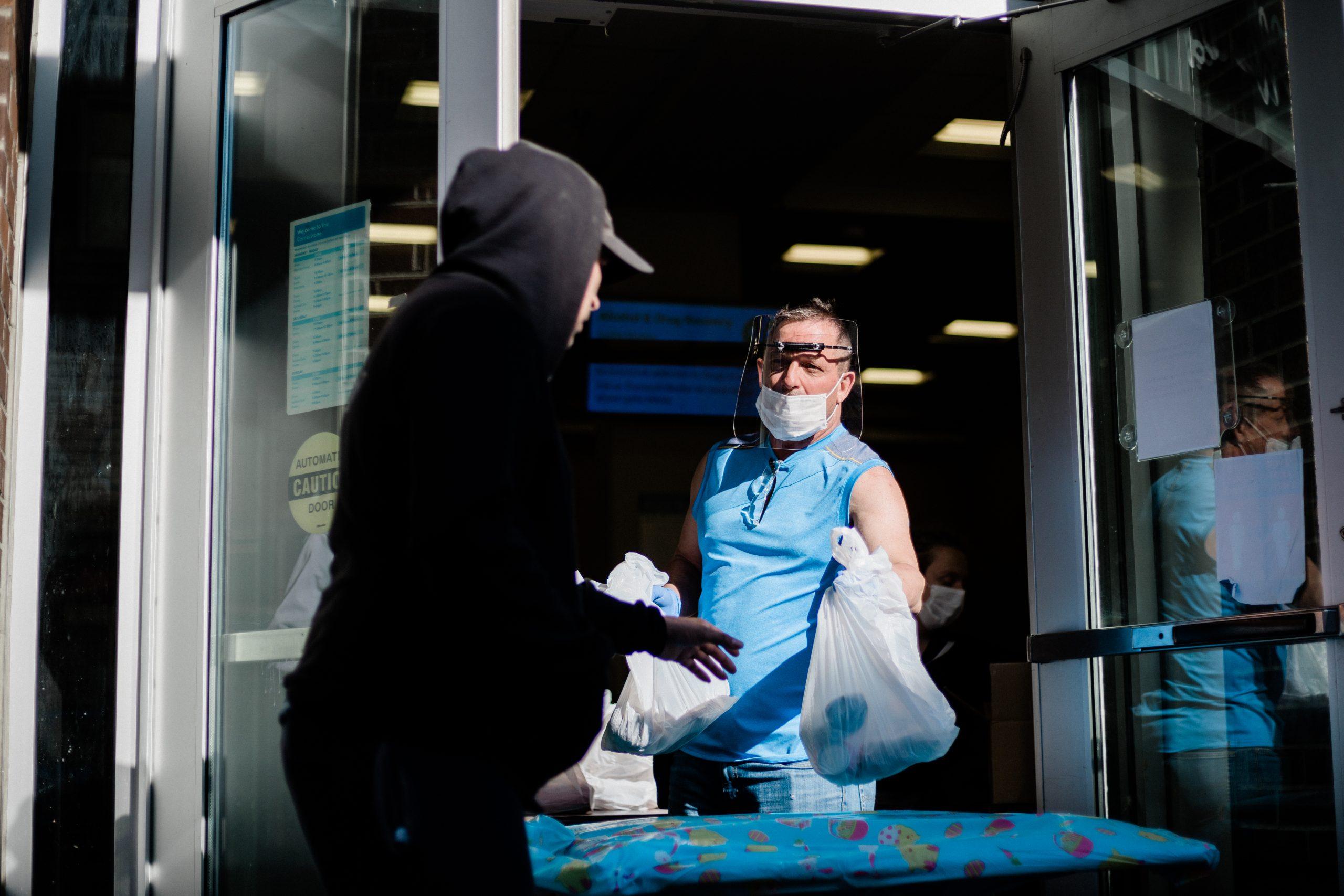 One man passes a bag of food to one another.