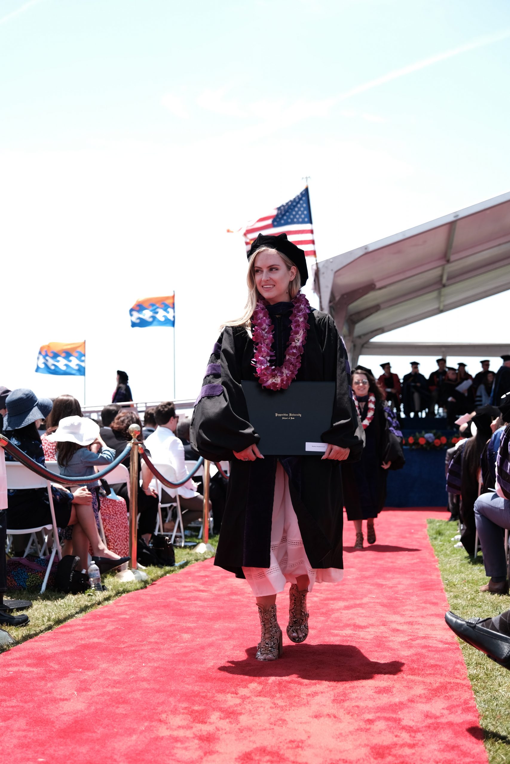 Female graduate walking a red carpet with her diploma.