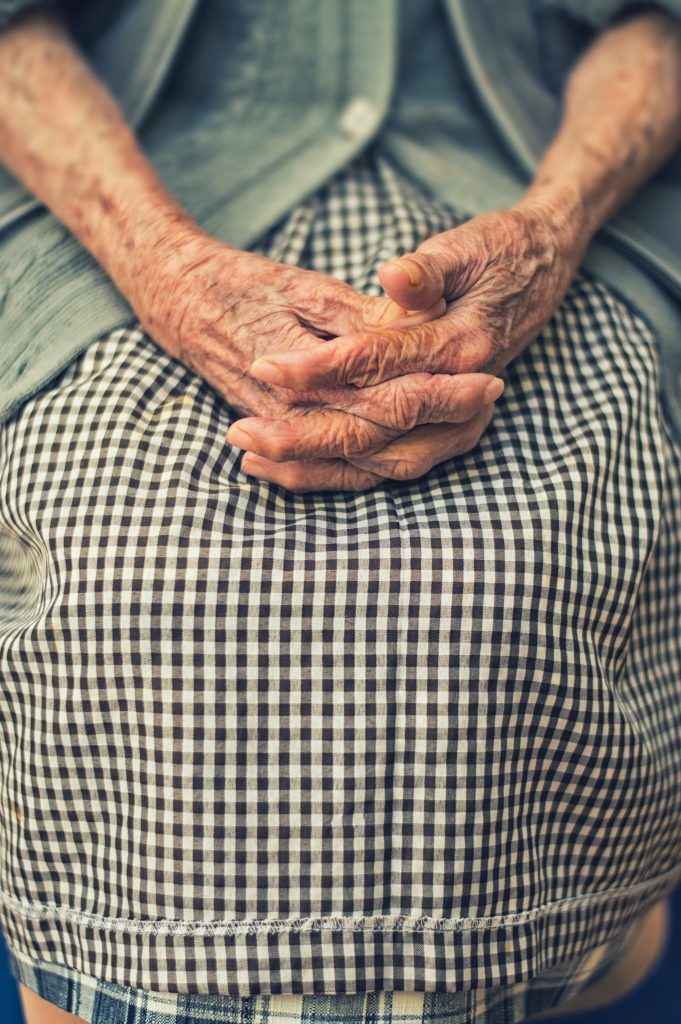 Elderly person hands folded on lap