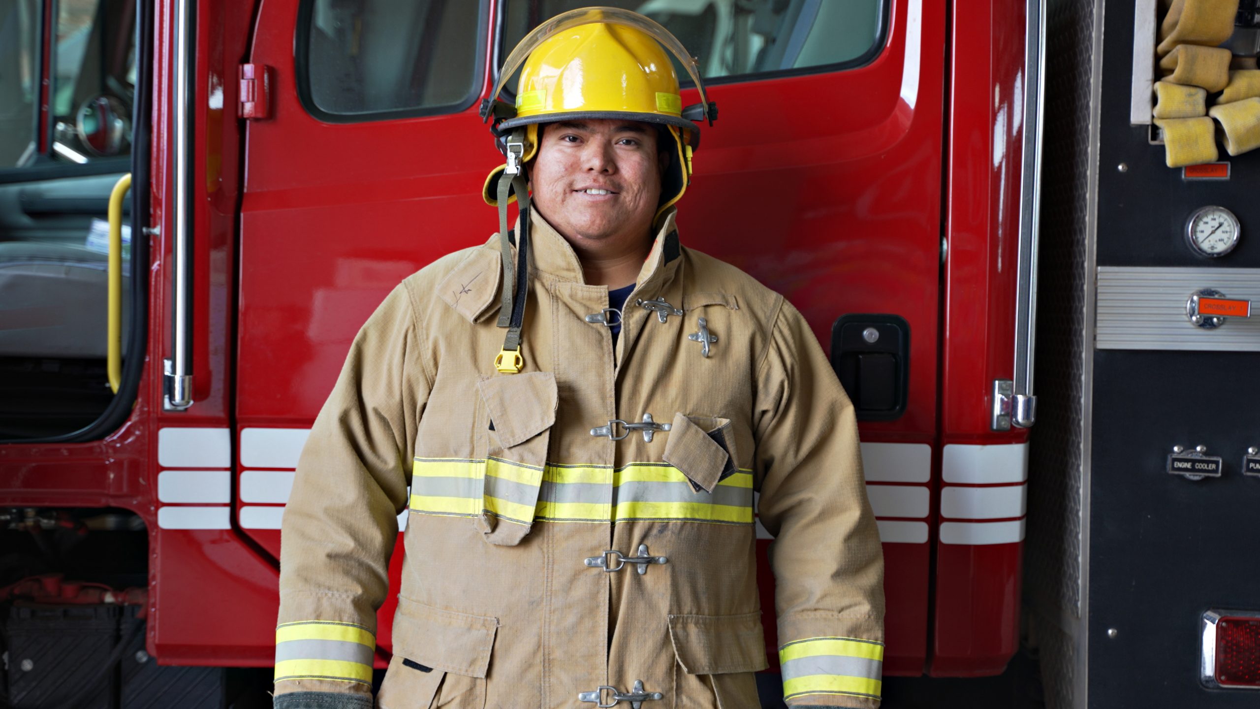 Indigenous Navajo Firefighter with protection suit standing in front of a fire engine truck