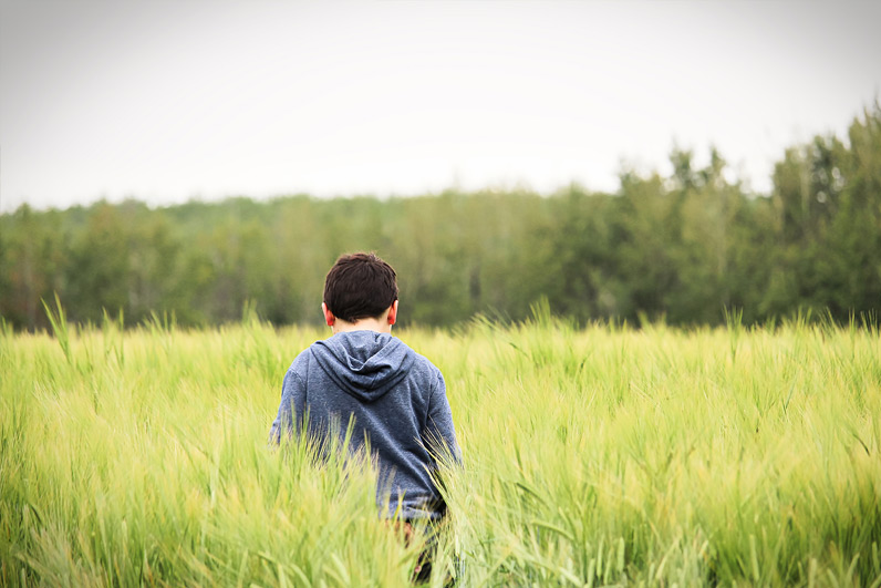 child standing in field of grass