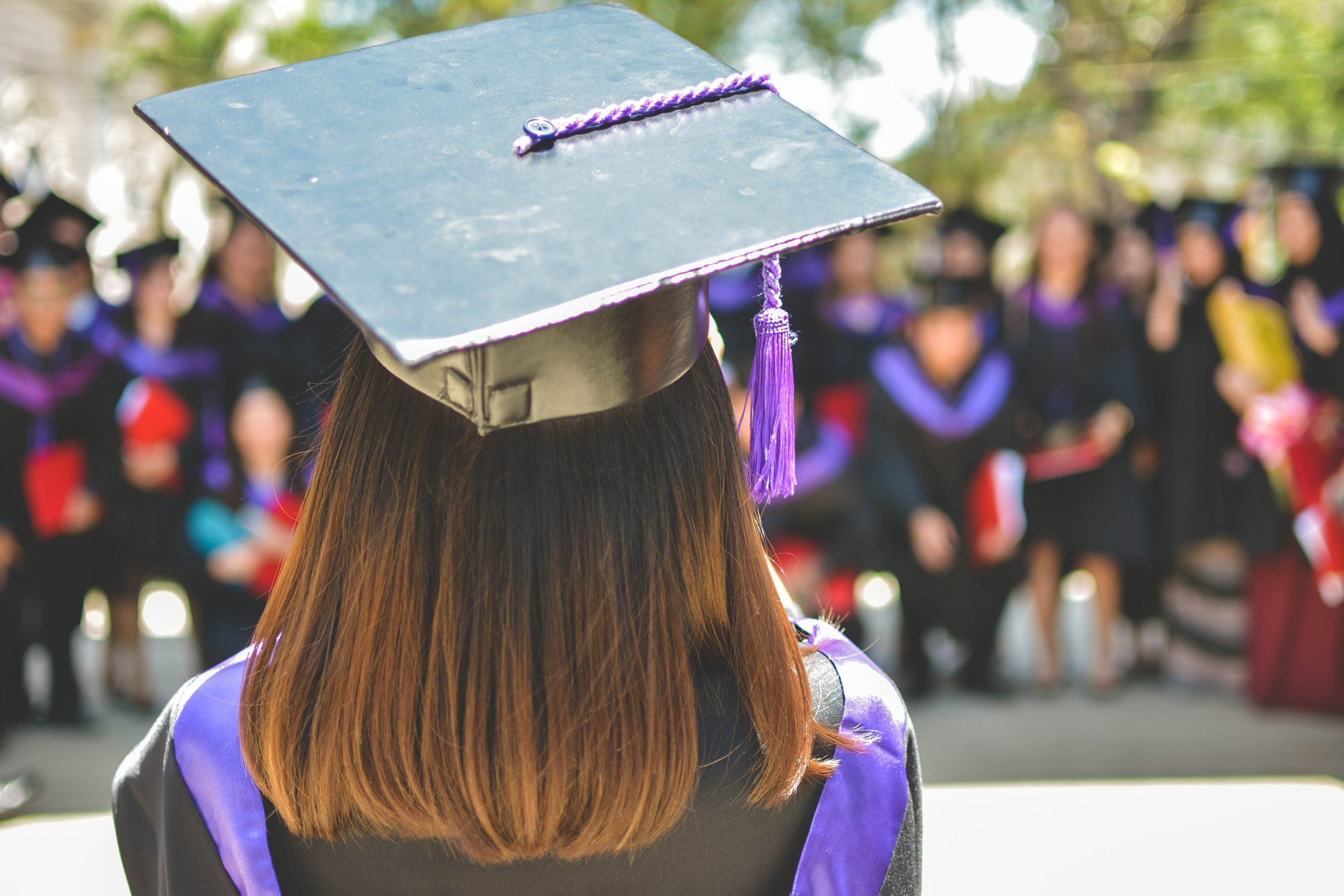 woman wearing academic cap and dress addressing graduating class