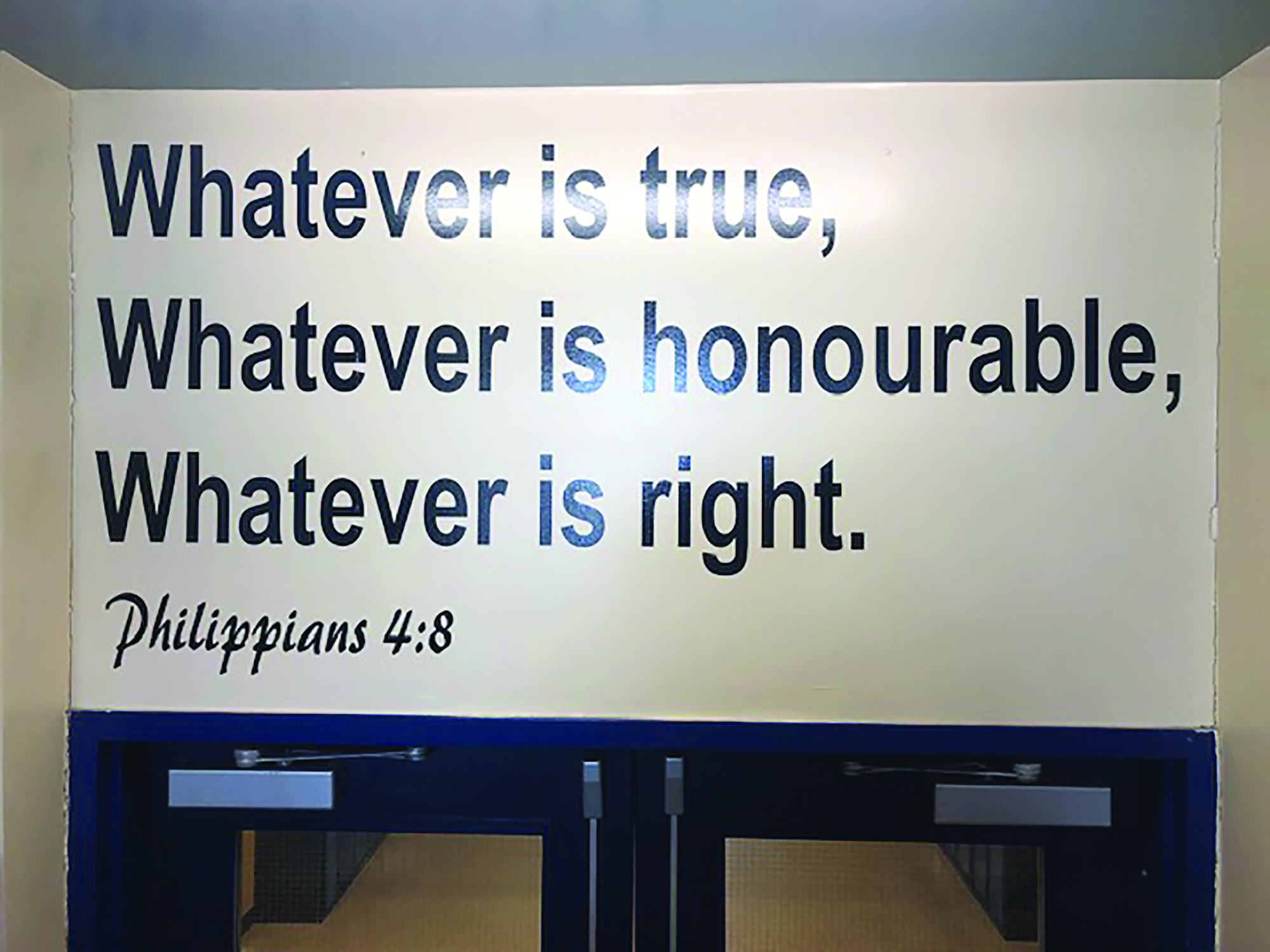 Sign containing bible text above school doors.