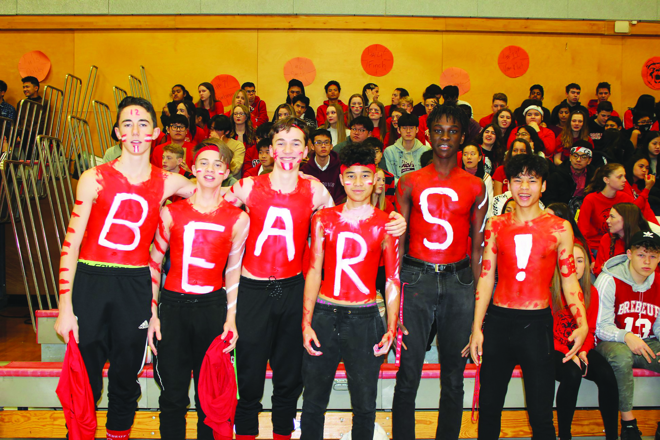Students stand in front of filled bleachers with "B-E-A-R-S-!" painted on their chests.