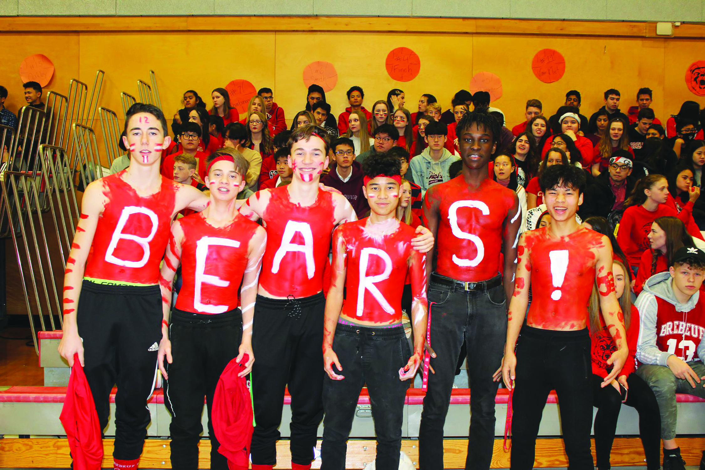 Students stand in front of filled bleachers with "B-E-A-R-S-!" painted on their chests.