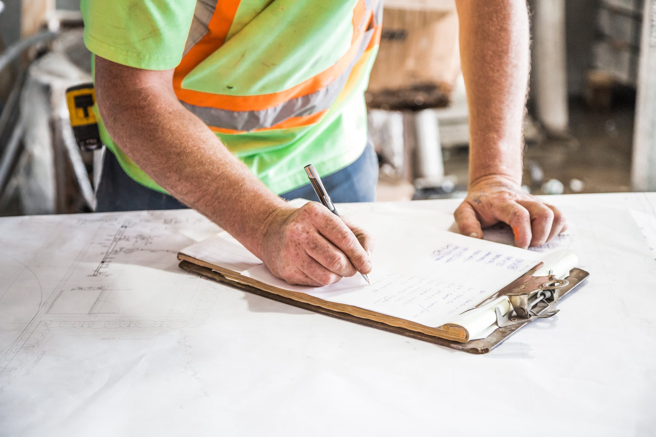 Trades Person Writing on Paper on Top of Table