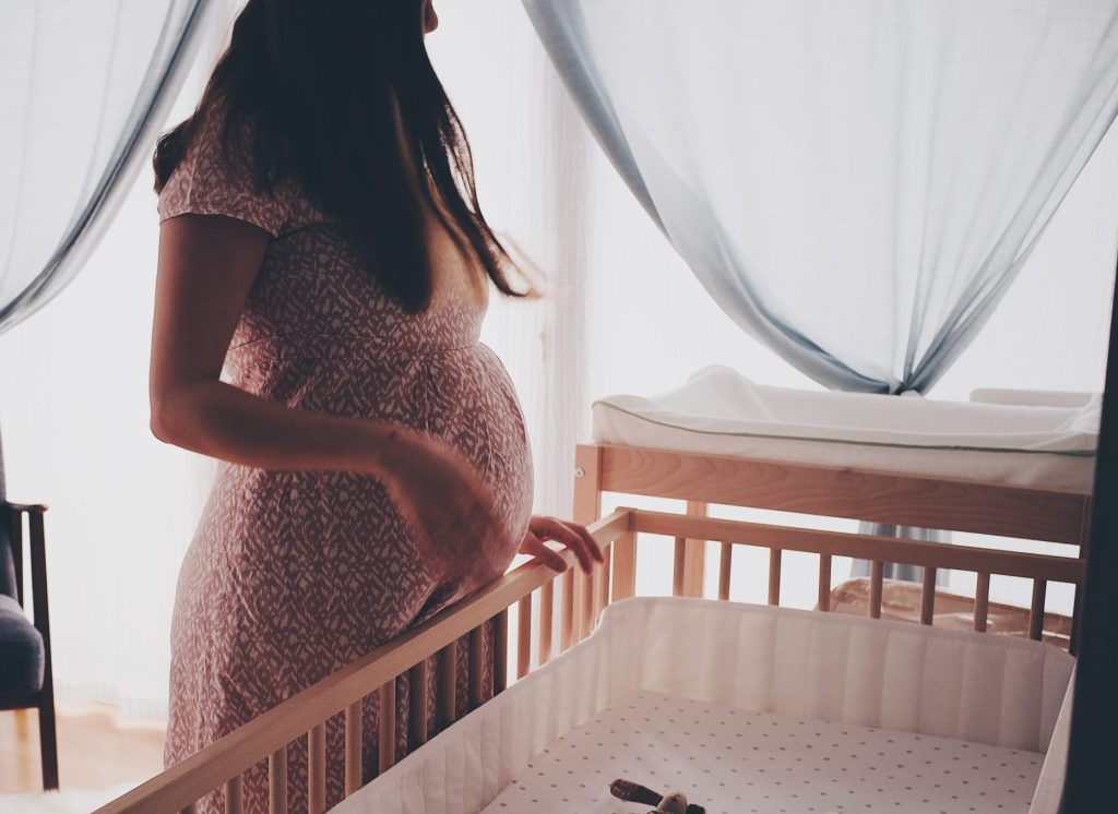 Pregnant woman standing over crib